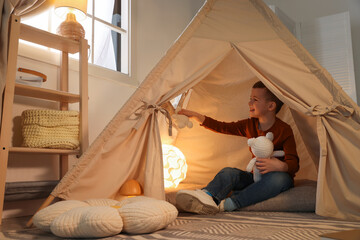 Little boy playing with toys in wigwam at home © New Africa