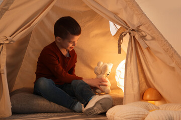 Little boy playing with toys in wigwam at home © New Africa