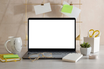 Fototapeta premium Stylish workplace. Laptop with blank screen, cup of coffee, houseplant and decor on white wooden table