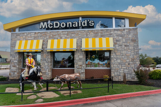 Weatherford, Texas: A western-theme McDonald's features an outdoor statue of Ronald McDonald lassoing a calf. Cowboy Ronald McDonald with cowboy hat riding a horse.