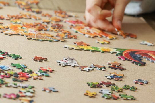 A teenage girl is putting together a puzzle. Only her hands are visible.