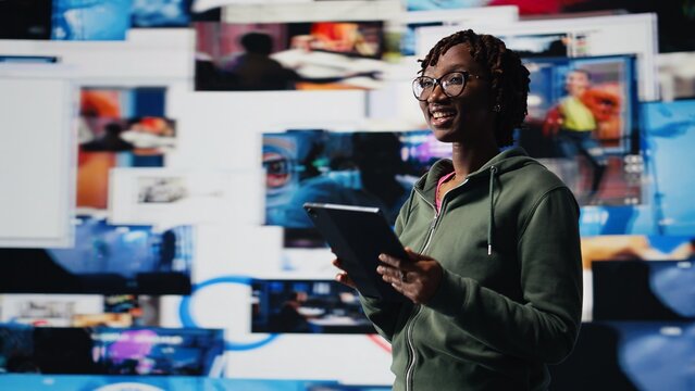 Smiling woman using tablet pleased by access to video recommendations delivered instantly. Joyous user excited by digital era enabling unlimited streaming, looking at clips on device, camera A