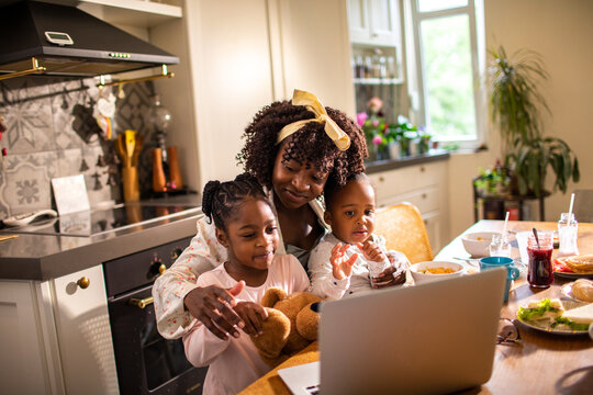 Mother and children video calling at breakfast in home kitchen
