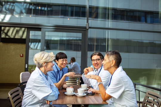 Doctors and nurses chatting over coffee on hospital terrace