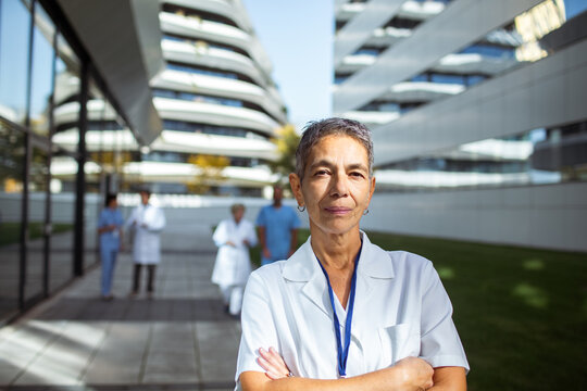 Confident senior female doctor outside modern hospital