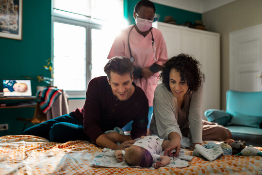 Parents and nurse caring for newborn at home