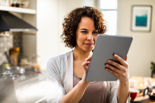 Smiling woman using tablet in home kitchen