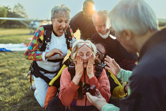 Older friends celebrating skydiving proposal at airfield