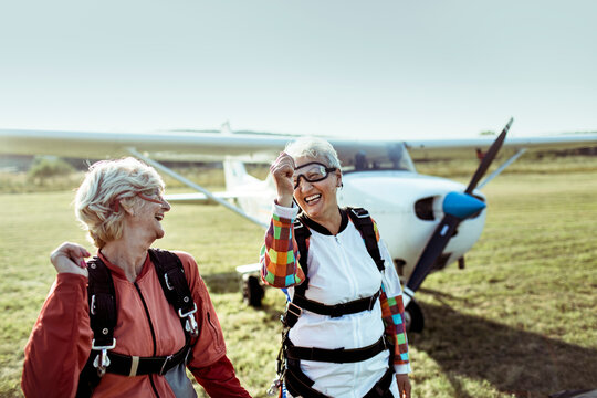 Two senior women celebrating after skydiving at airfield