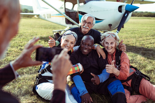 Group of senior friends after skydiving near airplane