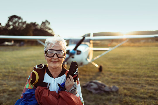 Senior woman skydiver with parachute at airfield at sunset