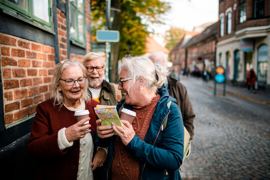 Senior friends reading map on historic cobblestone street