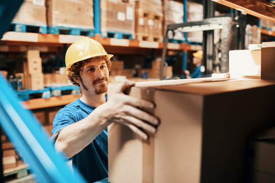 Warehouse worker handling cardboard boxes on storage shelves