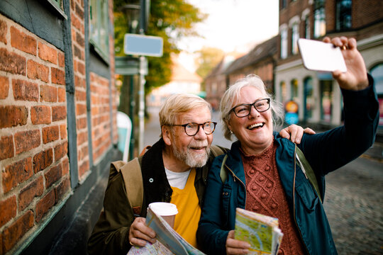 Smiling senior couple taking selfie while sightseeing in a european city street