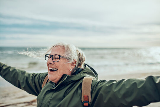 Happy senior woman enjoying a windy beach day