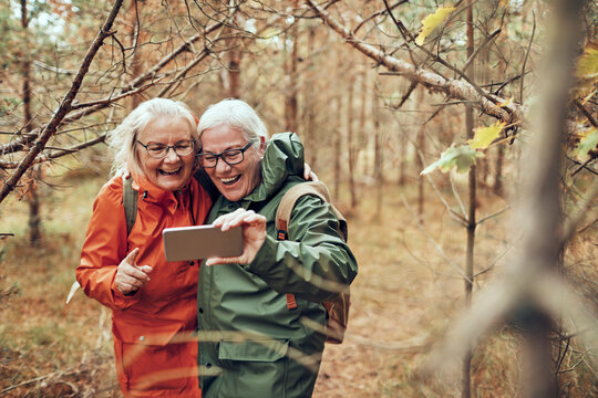 Two senior women taking a selfie while hiking in autumn forest