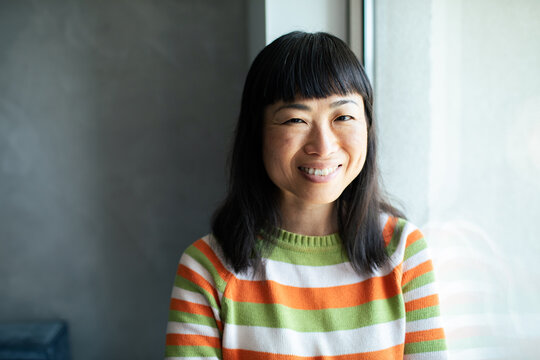 Smiling woman by window in striped sweater indoors