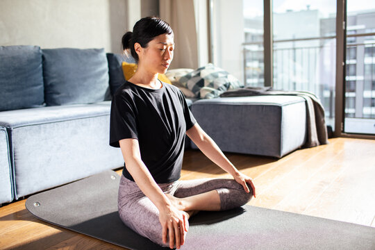 Woman meditating on yoga mat at home