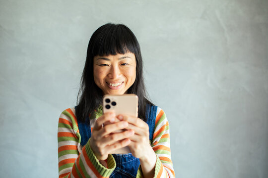 Smiling woman using smartphone at home with copy space