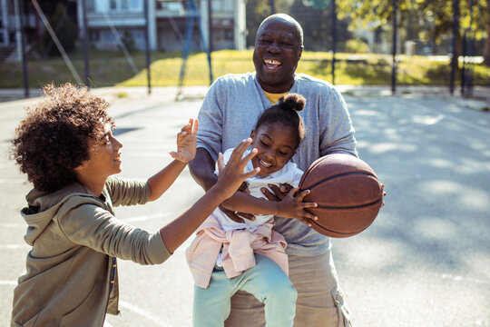 Grandfather and kids playing basketball at park