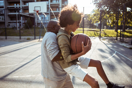 Father and son playing basketball at city park court