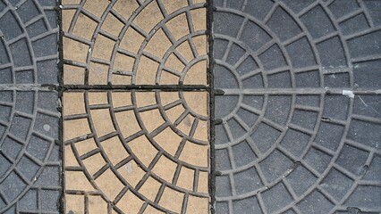 Geometric concrete paving tiles arranged in a repeating circular pattern across the outdoor ground surface area © Sueliton
