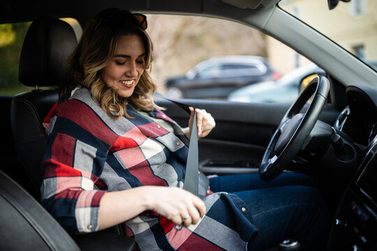Woman buckling seat belt in car, prioritizing safety