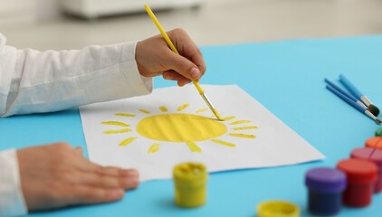 Little boy drawing picture with paints and brush at table, closeup