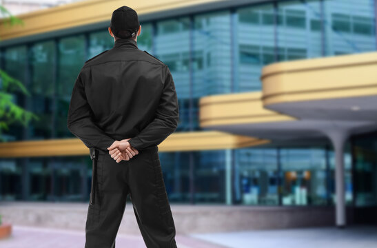 Security guard in uniform against building outdoors, back view