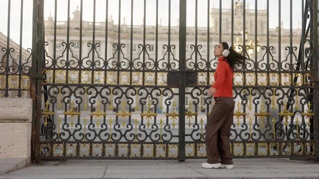 Happy young woman dancing in Madrid royal palace with headphones