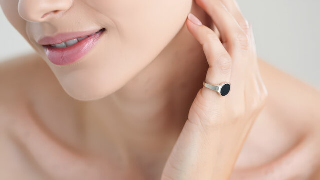 Smart fertility ring on a woman's hand near jawline, wearable ovulation sensor for basal body temperature monitoring, femtech wearable device for hormonal tracking, compact fertility tracker