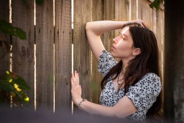 Obraz premium Young woman by wooden fence in warm sunlight