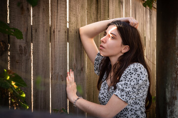 Obraz premium Young brunette woman by rustic wooden fence
