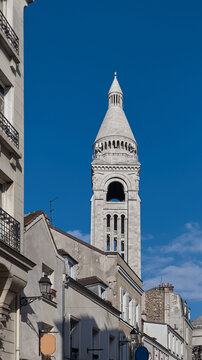 Sacre Coeur basilica tower rising above Montmartre roofs under blue spring sky