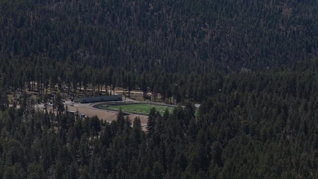 Aerial of football field in pine forest in Cloudcroft New Mexico sunny spring day