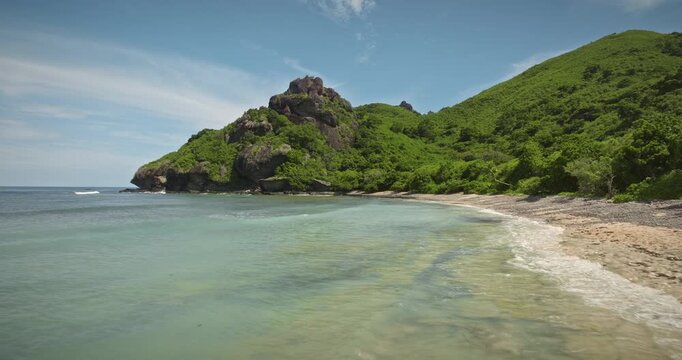 Fiji, Monuriki Island, remote tropical paradise stunning landscape with lush green hills, dramatic rock formations, and clear turquoise ocean waters meeting a rugged wild beach. Drone zoom out flight