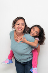 Fototapeta premium Latina single mom and her 5-year-old brunette daughter show their love with kisses and hugs to celebrate Mother's Day