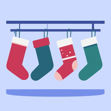 Cuatro calcetines navide&ntilde;os de colores rojo y verde cuelgan festivamente de una barra, listos para los regalos de la temporada.