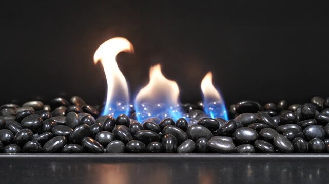 Blue core fire dancing polished black pebbles luxury fireplace styling crisp contrast cinematic flame visual