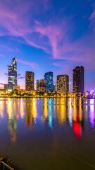 Fototapeta premium Illuminated cityscape reflecting in calm water under a vibrant twilight sky
