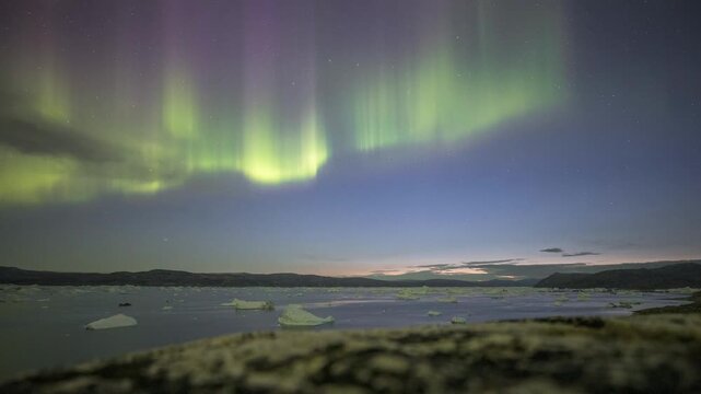 Timelapse of Northern Lights, Aurora Borealis dancing over ice fjord of East Greenland