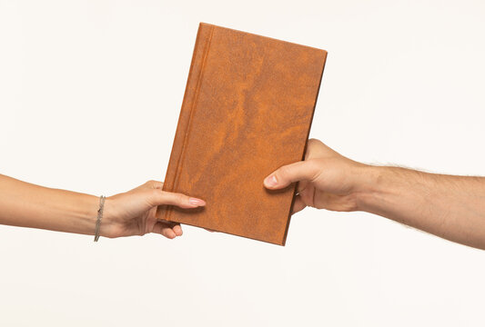 two persons holding a brown hardcover book with their hands on different sides