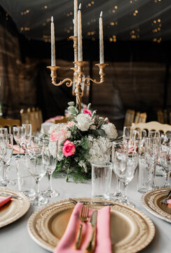 Centro de mesa con candelabro dorado y arreglo floral en elegante mesa de celebraci&oacute;n