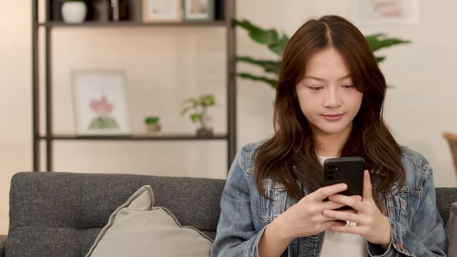 Young Asian woman scrolling dating app on smartphone at home