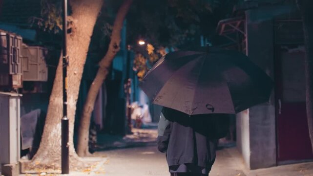 Night alley umbrella solitude urban walk, person in dark coat moves under raindropspeckled canopy, lamp glow, wet pavement reflecting neon signs, tree trunks framing narrow corridor, cinematic