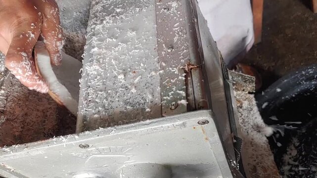 A hand grating coconut using coconut grater machine	