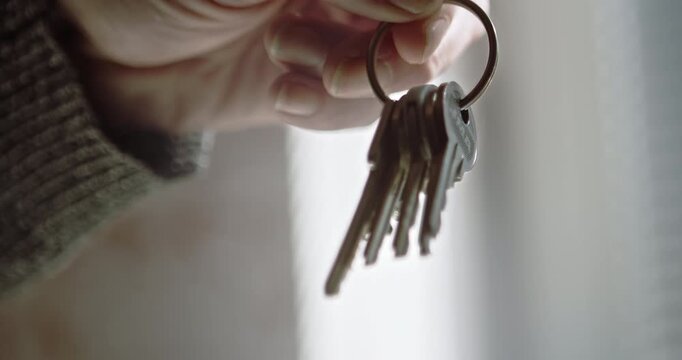 A close-up shot of a hand dangling a set of house keys and house keys. Ideal for automotive access and property ownership concepts.