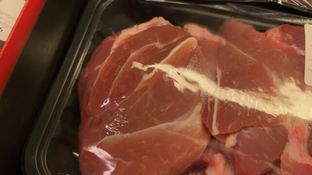 Closeup of raw meat in plastic tray with wrap packaging displayed for sale showing food storage and retail presentation in market setting
