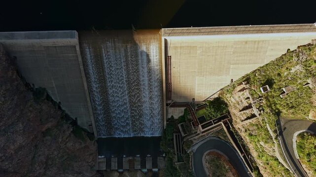 Aerial top down view of the Parralillo dam in Gran Canaria. The concrete structure holds back a large reservoir with overflowing water
