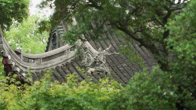 Ornate Chinese temple roof framed by lush foliage, cinematic slow pan, soft overcast light, weathered stone carvings, moss, tranquil garden ambiance, closeup architectural detail